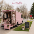 Un camion boutique coloré garé dans un parc, prêt à vendre des produits artisanaux.